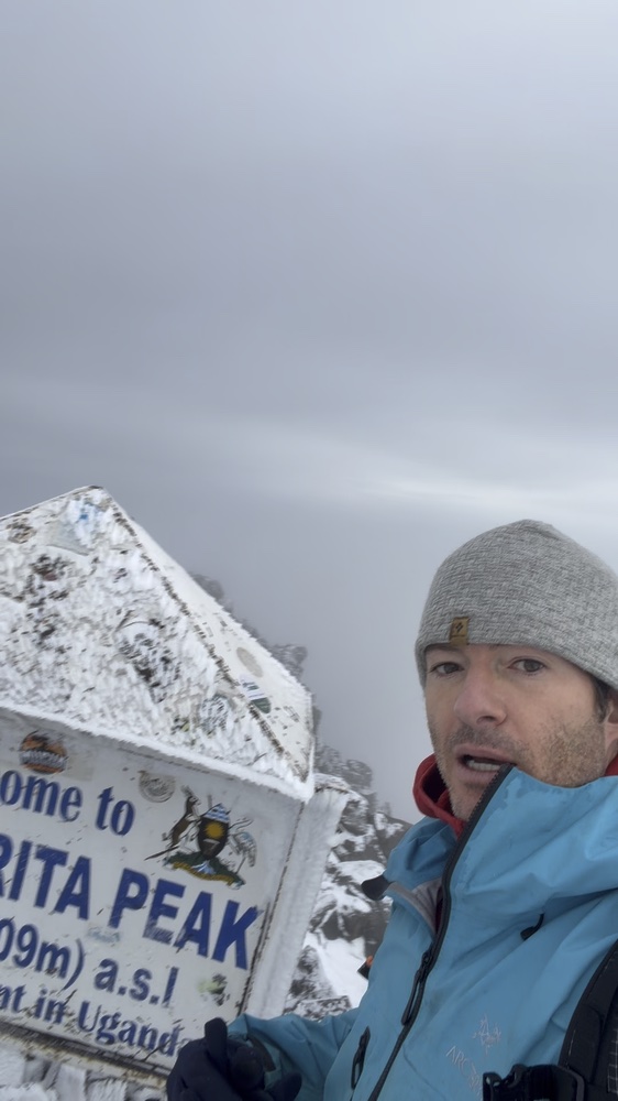 Climber beside the snowy Margherita Peak summit marker