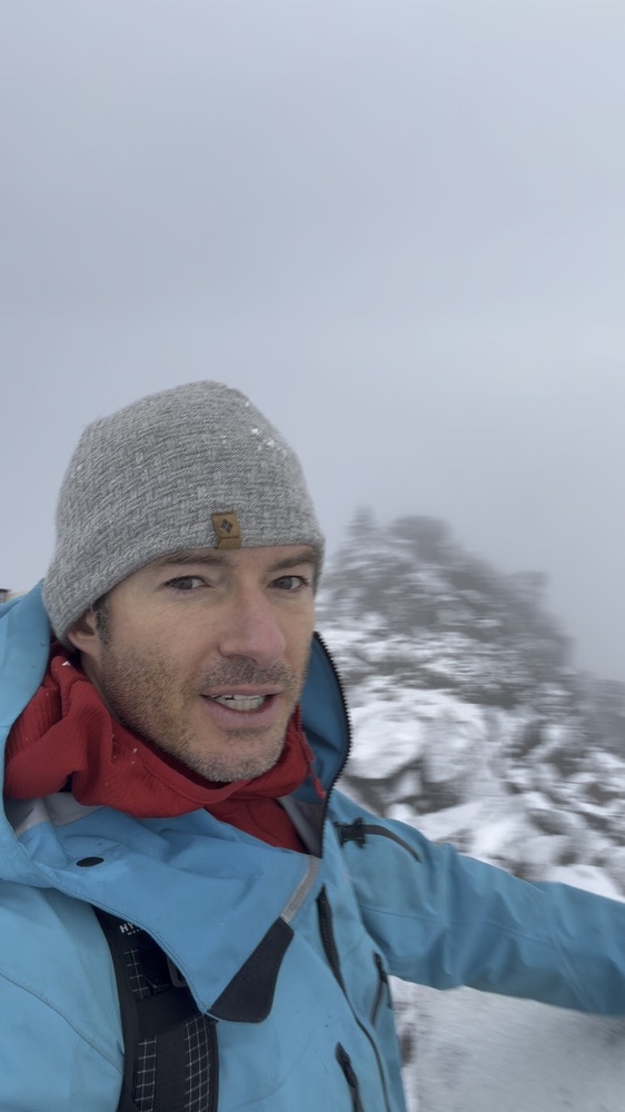 Summit selfie with snow-covered rocks behind