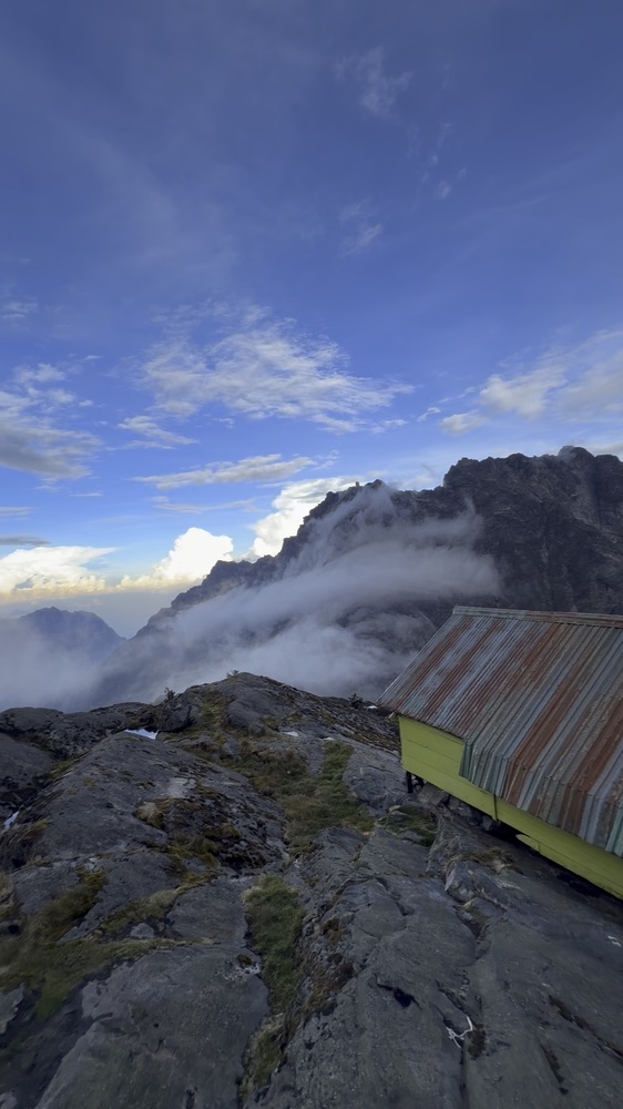 Mountain huts on bare rock beneath blue sky and cloud